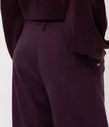 Pantalón de sastrería corte recto, color negro, con pliegues delanteros, cierre de botón y cremallera, y cinturón integrado con hebilla metálica.