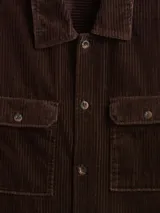 Sobrecamisa de pana color verde oliva, con cuello clásico, cierre frontal de botones y dos bolsillos delanteros con solapa.