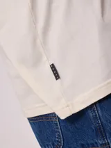 Remera de algodón con lavado, color crema o blanco roto, de corte regular fit y manga corta. Presenta un pequeño logo bordado en el pecho.