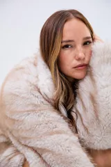 Campera de piel sintética en tono beige con textura suave y voluminosa. Presenta cuello alto, cierre frontal completo y mangas largas con puños amplios.