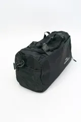 Bolso de viaje gris con doble asa corta y cierre superior. Estampado frontal con la frase "The Tote Bag" en letras blancas.