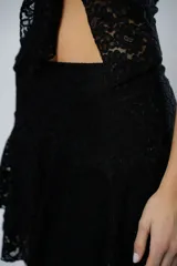 Pollera corta de encaje negro con diseño de volados escalonados y terminación con borde festoneado.