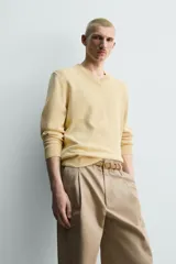 Sweater de punto en mezcla de algodón, color beige, con cuello en V y mangas largas. Presenta terminaciones en rib en cuello, puños y ruedo.