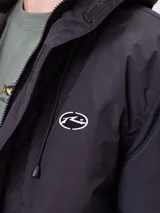 Campera técnica de invierno marca Rusty, color negro, con capucha ajustable, cierre frontal con solapa y bolsillos laterales. Presenta logo de la marca estampado en blanco en la manga y en el pecho.