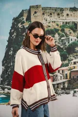 Cardigan oversized de punto grueso, color azul marino y blanco con franjas rojas y rosadas en el cuello, puños y solapa. Tiene botones grandes marrones y el logo de Anthea bordado en el pecho.