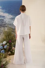 Blusa de lino color blanco, con silueta amplia, cuello mao y cartera frontal con botones dorados.