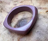 Pulsera rígida de forma cuadrada con bordes redondeados, color lila.