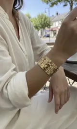 Brazalete ancho de bronce con diseño de eslabones entrelazados de acabado pulido y estructura ajustable.