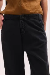 Pantalón de jean de tiro bajo y calce relajado, con cierre frontal de múltiples botones visibles y largo al tobillo.