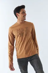 Remera color caramelo de manga larga con cuello redondo y estampado frontal con texto.