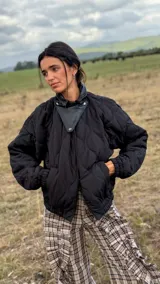 Campera puffer negra con diseño matelaseado en rombos, cuello alto con detalle de solapa en cuero sintético, mangas largas con puños elásticos y ruedo ajustado tipo bomber.