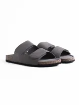 Sandalia de dos tiras con cierre de velcro, confeccionada en material símil cuero color gris. Cuenta con plantilla anatómica con base de corcho y suela de goma negra.