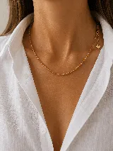 Collar corto tipo gargantilla compuesto por pequeñas cuentas facetadas en tonos ámbar y transparentes, con cadena de alargue y dije de corazón en el extremo.