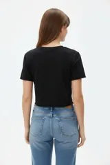 Remera cropped de algodón negra con cuello a la base, mangas cortas y estampado frontal de cerezas con la palabra "HELLO".