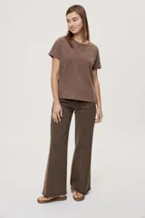Pantalón jean de tiro medio, color negro, de corte amplio y silueta extra wide leg. Presenta diseño clásico de cinco bolsillos, cierre frontal con botón y cremallera, y detalle de tachas metálicas aplicadas a lo largo de los laterales.