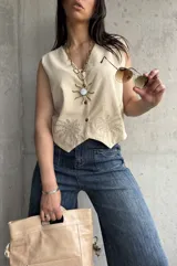 Chaleco color crema de lino liviano con bordado de palmeras en la terminación y corte recto.