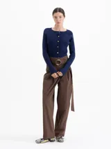 Cardigan de punto acanalado en color azul marino, con ajuste al cuerpo, mangas largas raglán y cierre frontal con botones dorados.