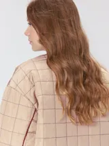 Campera reversible capitoneada con cierre frontal. Un lado es de color negro y el otro es de color beige, ambos con diseño acolchado. Cuenta con cuello redondo, mangas largas y bolsillos laterales.