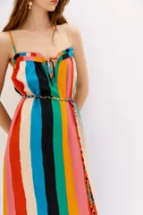 Vestido midi de tirantes finos con estampado de rayas verticales multicolores. Presenta un escote con detalle de fruncido y lazo, y un ruedo con volado que aporta movimiento a la prenda. Incluye un cinturón trenzado a juego en la cintura.