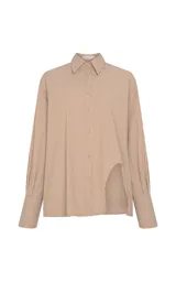 Camisa de corte recto y diseño oversize, con estampado de rayas verticales en tonos marrón y blanco. Presenta cuello clásico estructurado, mangas largas con puños anchos, hombros caídos y bajo asimétrico con abertura lateral. Cierre frontal mediante botones.