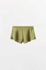 Shorts de tiro alto confeccionado en tejido satinado color verde oliva, con cintura elástica, bajo con volantes y aberturas laterales decoradas con aplicaciones de encaje a tono.