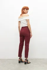 Pantalón de vestir color bordó, de corte recto, con bolsillos laterales y traseros. Se ajusta a la cintura con cinturón de cuero marrón.