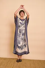 Vestido midi amarillo y blanco con estampado de paisajes y detalles de rayas en el cuello y el dobladillo, de corte holgado, mangas cortas y lazo ajustable en la cintura.
