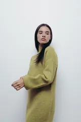 Vestido corto de punto color fucsia, con cuello alto y mangas largas amplias. Diseño holgado y cómodo.