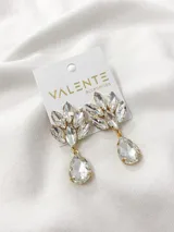 Aros colgantes dorados con cristales transparentes en forma de hojas y gota.