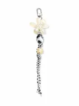 Llavero con gancho metálico plateado, dije de flor translúcida, cuenta marmolada en tonos blanco y negro, cuenta cúbica transparente y cordón trenzado en blanco y negro.