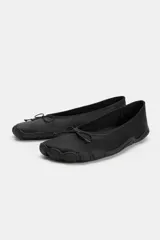 Zapato tipo bailarina deportiva de color negro, con suela de goma y detalle de lazo en la puntera redonda.