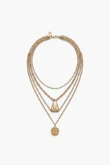 Collar de acero dorado de múltiples cadenas superpuestas con dijes colgantes, incluyendo dos dijes en forma de gota y una medalla texturizada.