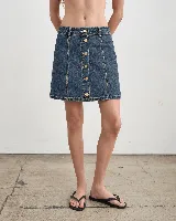Minifalda de denim azul con costuras pespunteadas en contraste y cierre frontal de botones metálicos dorados.