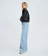 Pantalón wide leg de denim de algodón, con cintura media, cierre frontal con botón y cremallera, bolsillos funcionales y diseño con recortes transversales.