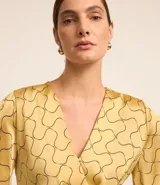 Blusa de mangas cortas con escote V traspasado, pliegues y recorte en la cintura. Confeccionada en tejido con efecto satinado y estampado geométrico con líneas curvas.