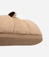 Pantufla cerrada de peluche color tostado con diseño de cara de oso en la parte frontal y orejas pequeñas. Cuenta con suela de goma antideslizante y forro interior suave.