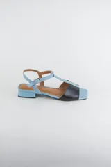 Sandalias de cuero combinadas en negro y marfil, con diseño de tiras en T, taco cuadrado bajo y pulsera con hebilla ajustable al tobillo.