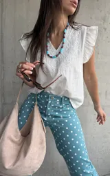Musculosa blanca de diseño ligero con escote en V y sutiles detalles bordados tonales en el frente, complementada con volados en las sisas.