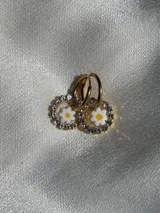 Aros colgantes con forma circular, con strass plateado alrededor y flor de vidrio amarilla con centro rojo en el interior. El arito es de acero quirúrgico.