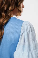 Blusa azul de cuello redondo y manga corta abullonada con puño elástico.