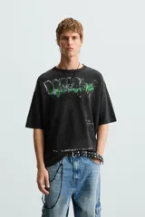 Camiseta boxy fit de punto tejido en hilatura de algodón, color negro con efecto lavado. Cuello redondo y manga corta. Estampado frontal con letras en blanco y verde.