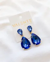 Aros colgantes con forma de lágrima, con dos cristales facetados azules engarzados en metal dorado.