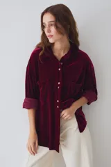 Camisa de terciopelo color beige, de corte oversize, con cuello camisero, cierre frontal de botones, bolsillos aplicados en el pecho y mangas largas con puños doblados.