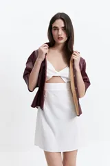 Camisa de manga corta confeccionada en cuero sintético color bordó, con cuello clásico, cierre frontal de botones metálicos y dos bolsillos frontales con solapa.