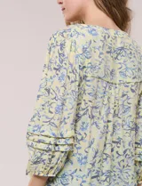 Blusa holgada de gasa estampada en tonos amarillos y azules, con cuello en V, mangas 3/4 abullonadas y alforzas horizontales.