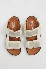 Sandalias planas color hueso, con doble tira con apliques de strass y ajuste con velcro.