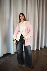 Saco oversize de tejido de punto en color rosa, con mangas caídas y detalles de bordado a mano en contraste en los bordes y costuras.