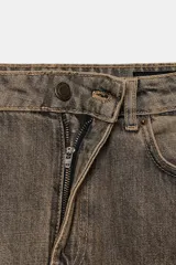Jeans de tiro medio con diseño de pierna curva tipo barrel, confeccionados en denim con efecto lavado. Presentan cintura con trabillas, cierre frontal con cremallera y botón, y cinco bolsillos clásicos.