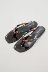 Ojota marrón con base cuadrada y tiras decoradas con piedras de colores y tachas doradas.