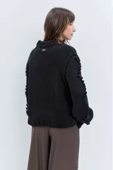 Sweater de punto grueso color rojo, con cuello alto y diseño de relieves tipo pompones en el frente y las mangas. Presenta puños y ruedo acanalados.